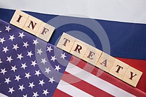 INF Treaty written wooden block letters in between the US and Russian Flag, Concept of INF treaty signed by US and Russia