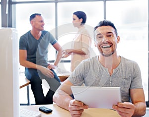 The infamous workplace LOL. Portrait of an office worker using a tablet while his coworkers have a discussion in the