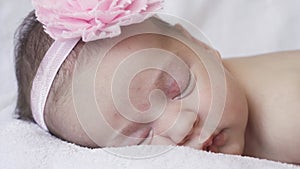 Infancy, childhood, development, medicine and health concept - close-up face of a newborn sleeping baby girl lying