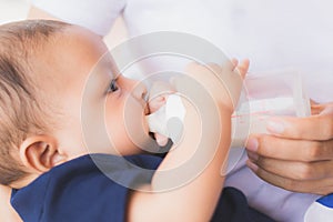 Infant baby on being fed by her mother drinking milk from bottle