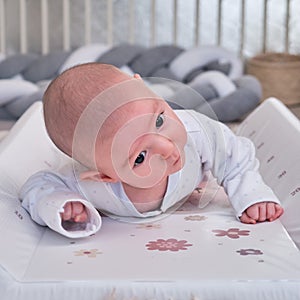 Infant baby boy exercising to keep his head lying on his stomach in the children`s room