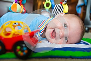 Infant baby boy playing on activity mat