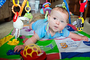 Infant baby boy playing on activity mat
