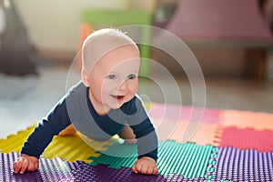 Infant baby boy playing on colorful soft mat. Little child making first crawling steps on floor. Top view from above