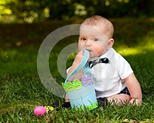 Infant baby boy playing with Easter eggs and basket