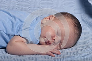 Infant baby boy sleeping on a blue blanket