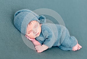 Infant baby boy sleeping in woolen costume with bare feet