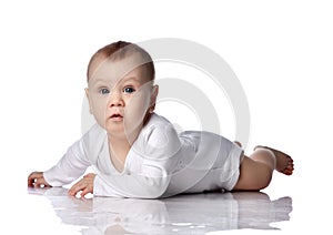 Infant baby boy toddler in diaper and white bodysuit is lying on floor on his stomach, crawling, watching unknown