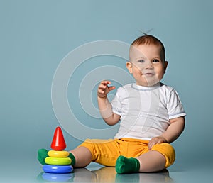 Infant baby boy toddler playing with a children multi-colored developing pyramid