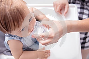 Infant baby girl drinks water from baby cup