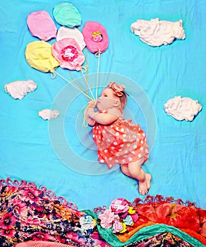 Infant baby girl flying on a helium balloons