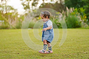 infant baby learning to walking first step on green grass in park