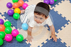 infant baby playing colorful balls in playpen