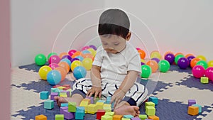infant baby playing wooden block toy in playpen