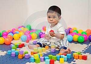 infant baby playing wooden block toy in playpen