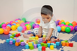 infant baby playing wooden block toy in playpen