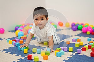 infant baby playing wooden block toy in playpen