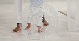 Infant barefoot baby boy learning to walk on warm floor