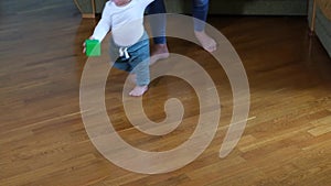 Infant barefoot baby girl boy learning to walk standing on warm floor.