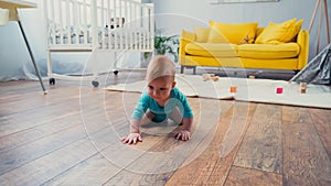 infant boy in blue romper crawling