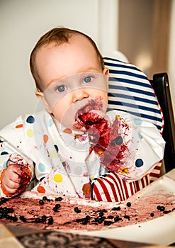 Infant boy eating alone with hands