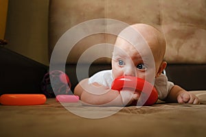 Infant boy playing with developing toy lying on sofa. Cute 4 month old baby boy. Child development concept.