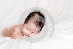 Infant boy sleeping on white bed