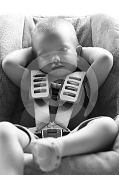 Infant boy sleeps peacefully secured with car seat belts