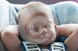 Infant boy sleeps peacefully secured with seat belts