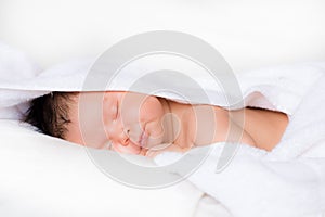 Infant boy smiles in his sleep on white bed