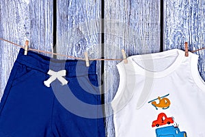 Infant boy summer clothes hanging on rope.
