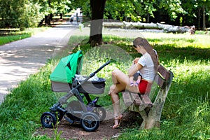 Infant breastfeeding outside scene, attractive young woman and new mother in red mini shorts is holding baby and nursing outdoor