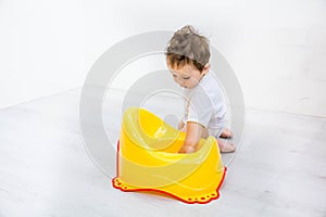 Infant child baby boy toddler play with potty toilet stool pot on a white background