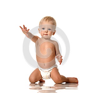 Infant child baby boy toddler sitting in diaper with hand up