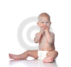 Infant child baby boy toddler sitting in diaper happy smiling eating hands playing isolated on white