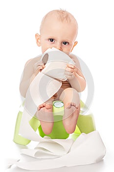 Infant child baby boy toddler sitting on potty toilet with a roll of toilet paper. stool pot isolated on a white background.