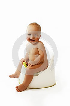 Infant child baby boy toddler sitting on potty toilet stool pot isolated on a white background.
