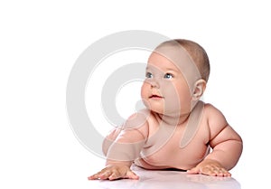 Infant child baby girl kid in diaper is lying on her stomach holding arm outstretched and looking aside