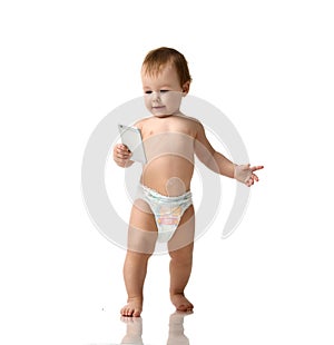 Infant child baby girl kid toddler in diaper make first steps with mobile cellphone on a white photo