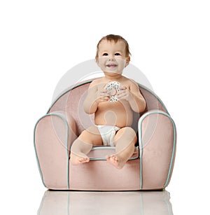 Infant child baby girl kid toddler in diaper sit in little armchair chair eat donut photo