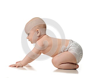 Infant child baby girl learning how to crawl in diaper looking a