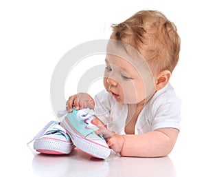 Infant child baby girl lying happy searching new shoes isolated