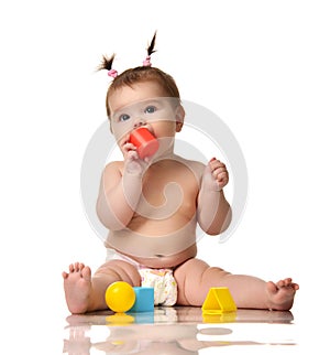 Infant child baby toddler sitting in diaper with yellow blue and red educational toys playing isolated