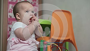 Infant, childhood concept - happy funny toddler kid 8 month baby girl sit lick playing Wooden and Wired Bead Maze Abacus