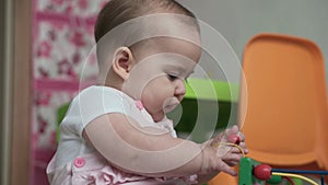 Infant, childhood concept - happy funny toddler kid 8 month baby girl sit lick playing Wooden and Wired Bead Maze Abacus