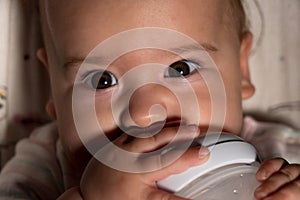 Infant, childhood, emotion, food concept - close-up of smiling face of big brown-eyed chubby newborn awake baby 7 months drinks