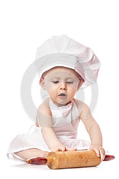 Infant cook baby portrait wearing apron and chef hat with dough rolling pin, isolated on a white background