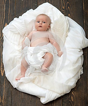 Infant covered with white blanket. Childhood and innocence concept.