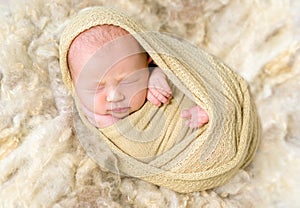 Infant enveloped tightly, resting, closeup