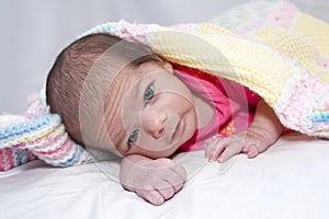 Infant girl covered with afghan